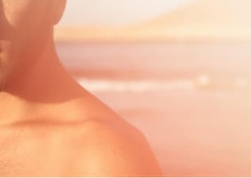 海辺で日差しを浴びる男性の肩